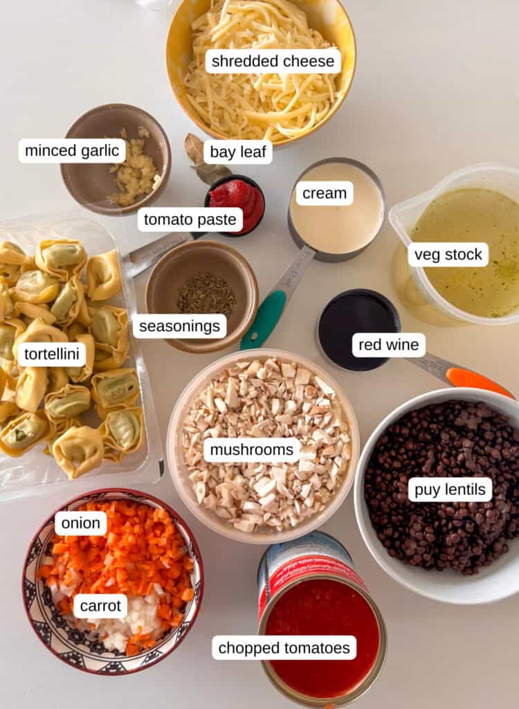 ingredients needed for baked tortellini lasagna: cheese, minced garlic, bay leaf, tomato paste, cream, veg stock, seasonings, tortellini, mushrooms, red wine, puy lentils, carrot, chopped tomatoes