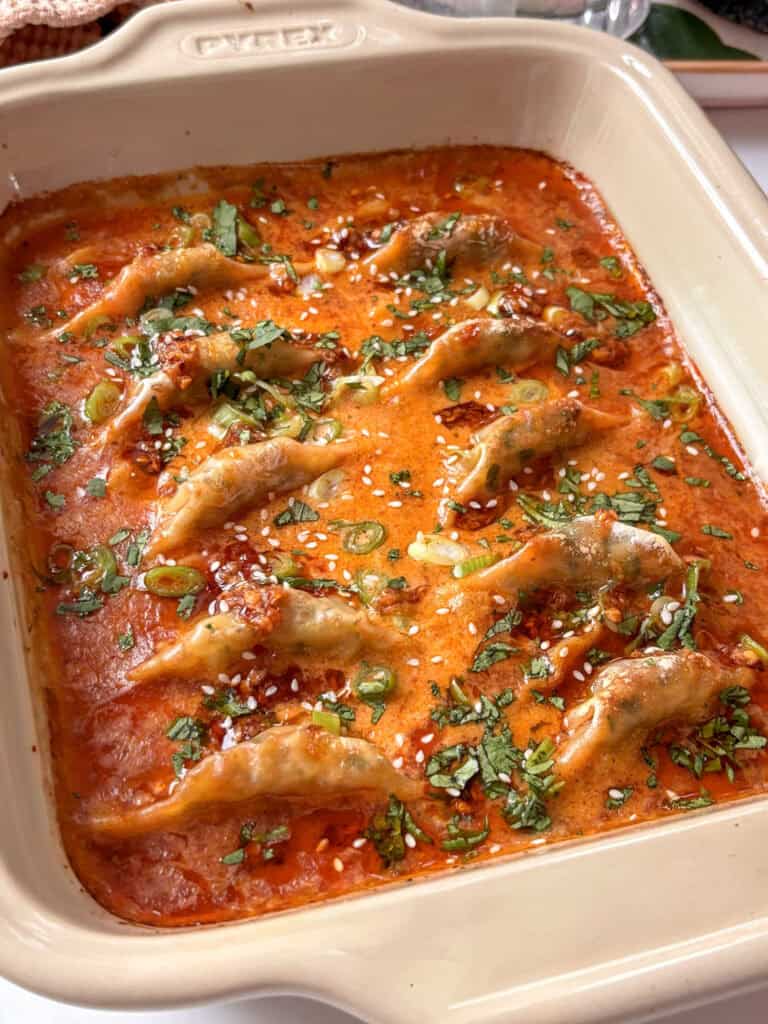 red curry dumpling bake topped with spring onions, cilantro, and chili crisp