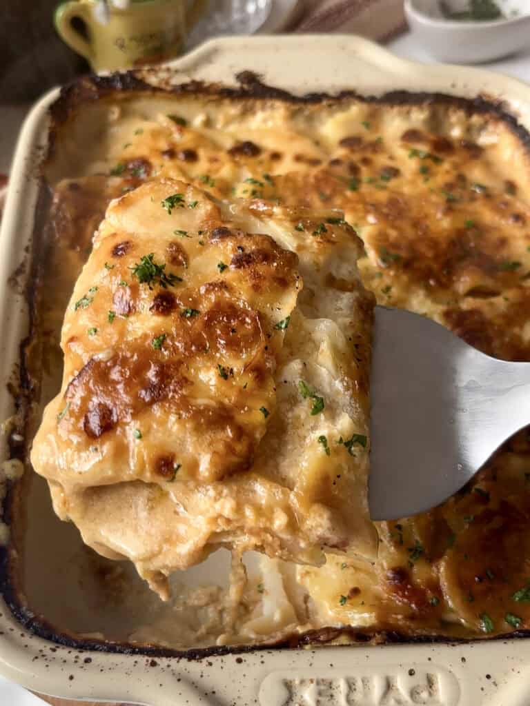cheesy Marmite potato bake portion begin lifted out of the pan