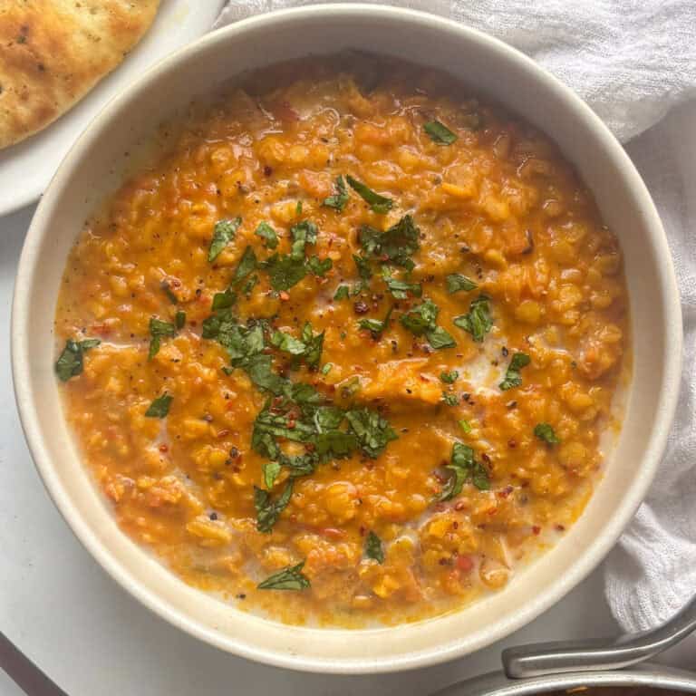 red lentil dahl in a bowl topped with fresh herbs