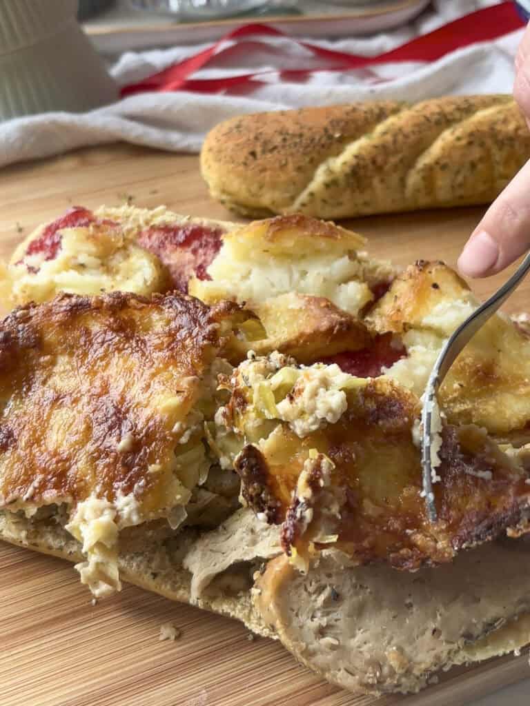 festive sandwich being layered up, with cheesy leeks being added