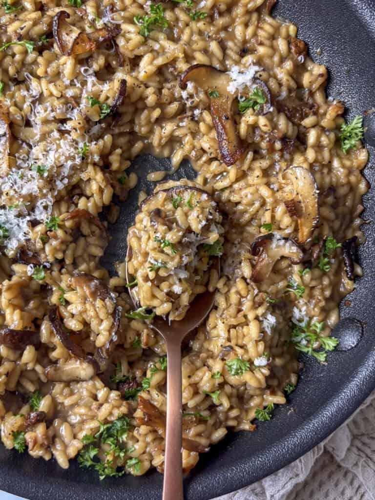 mushroom risotto with a spoonful being scooped out of the pan