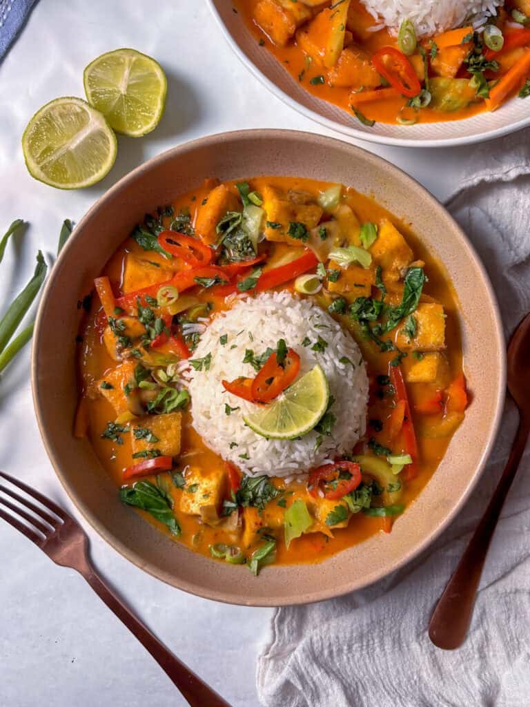 a gorgeous bowl of thai red curry served with rice, finished with cilantro, lime, and red chilli 
