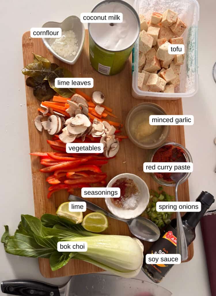 thai red curry ingredients: tofu, coconut milk, cornflour, lime leaves, vegetables, minced garlic and ginger, seasonings, red curry paste, lime, spring onions, soy sauce