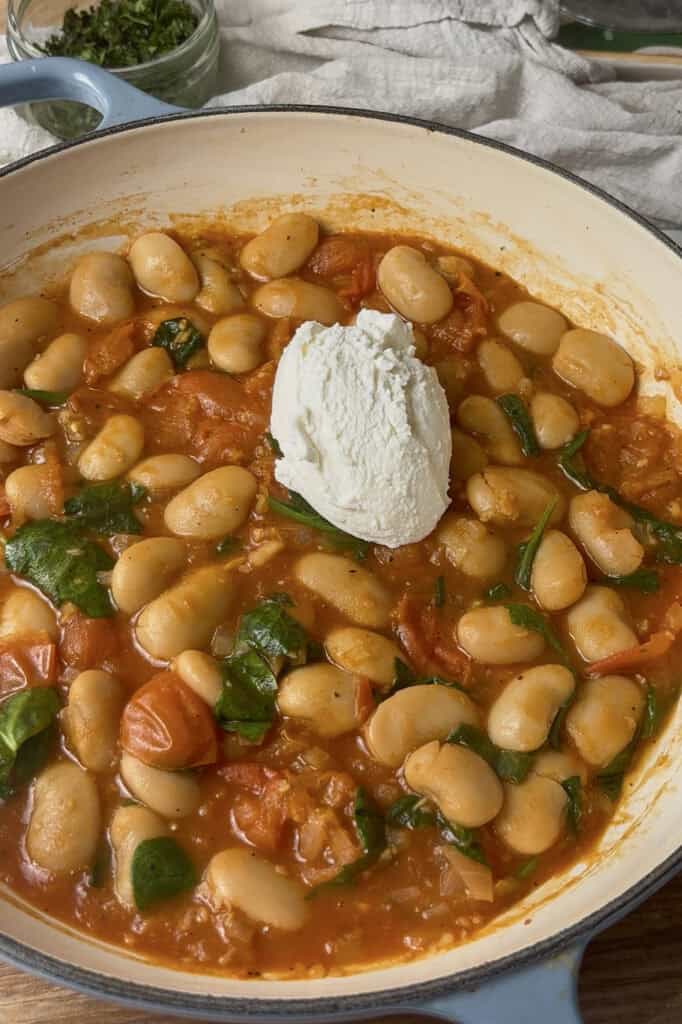 the cherry tomato butter beans are finished with a scoop of ricotta