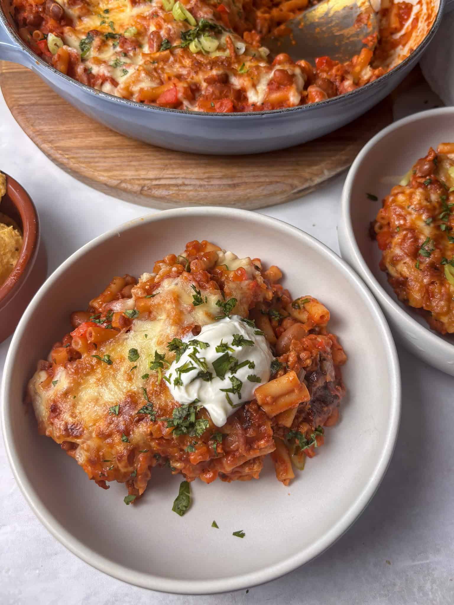 chili mac and cheese in a bowl topped with sour cream and cilantro
