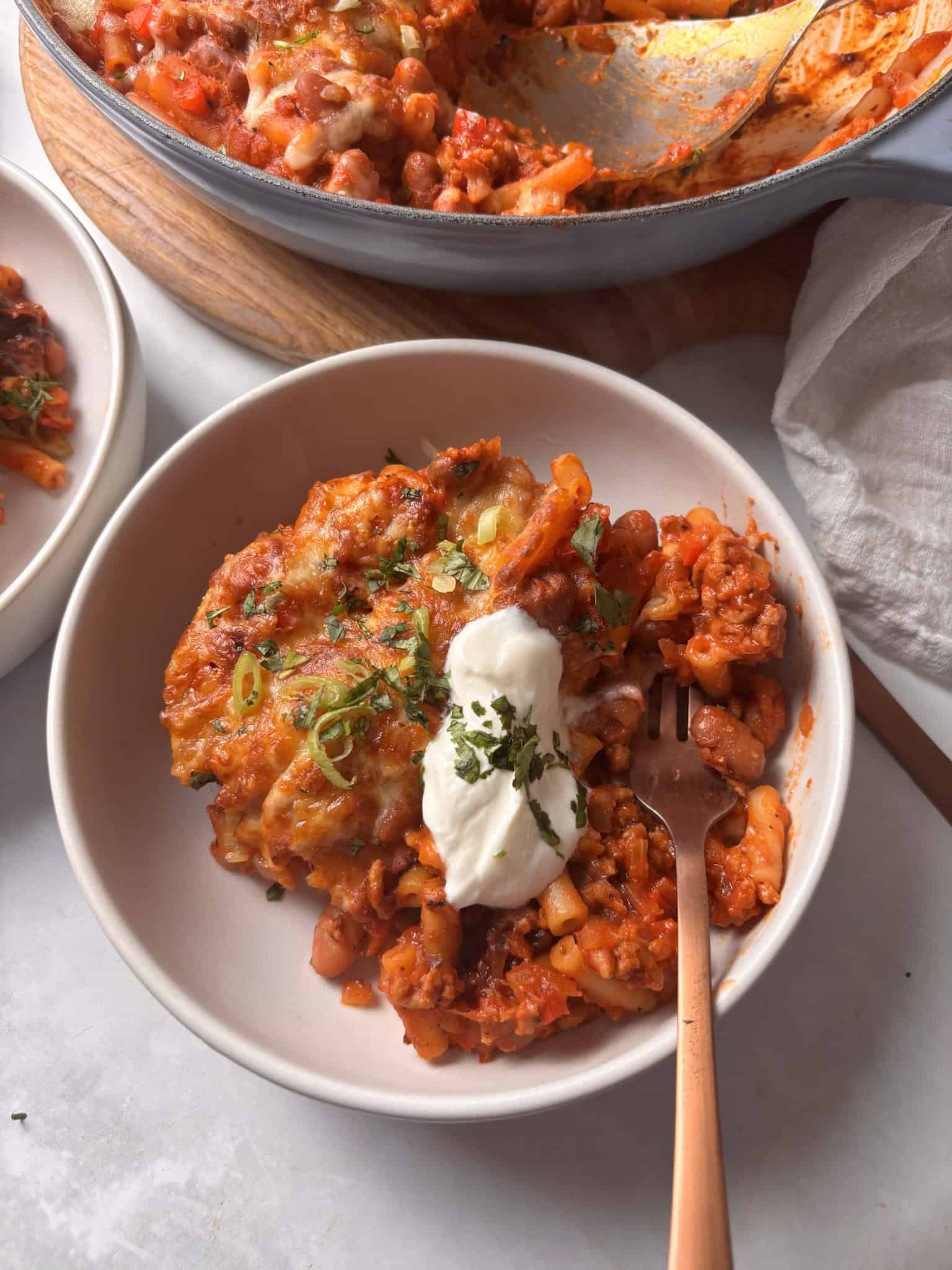 a bowl of cozy chili mac and cheese topped with sour cream and cilantro