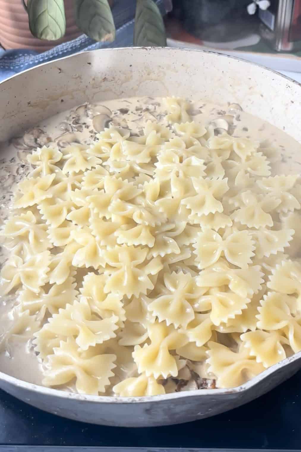 cooked pasta is added to the pan on top of a creamy mushroom sauce mixture