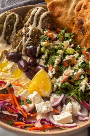 a bowl of homemade falafel, hummus, fresh vegetables, toasted pitta