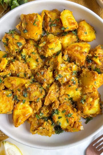 overhead photo of curried potatoes in a bowl topped with fresh cilantro