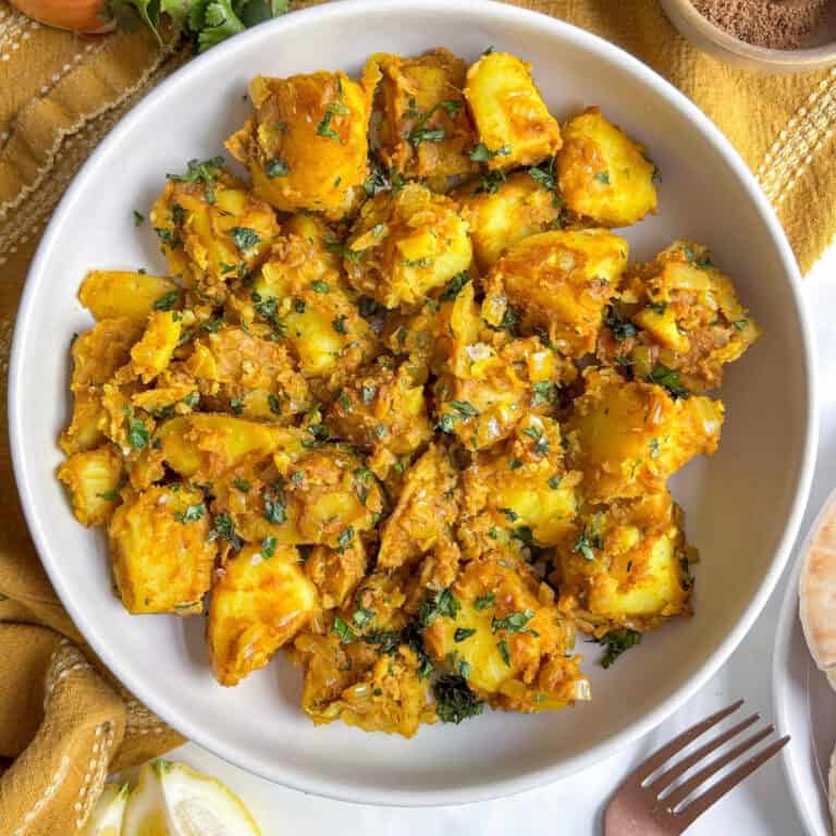 overhead photo of curried potatoes in a bowl topped with fresh cilantro