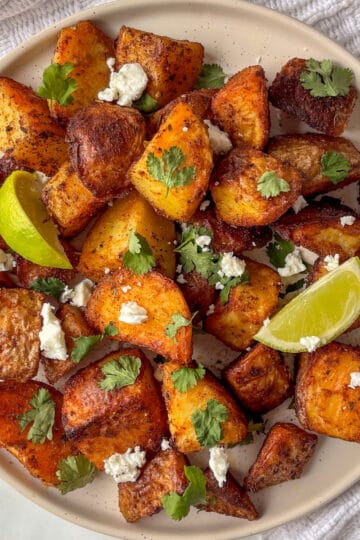 a plate of crispy Mexican potatoes topped with crumbled feta and cilantro leaves