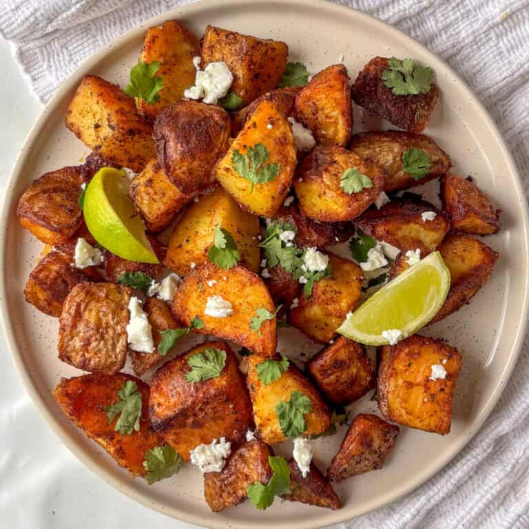 a plate of crispy Mexican potatoes topped with crumbled feta and cilantro leaves