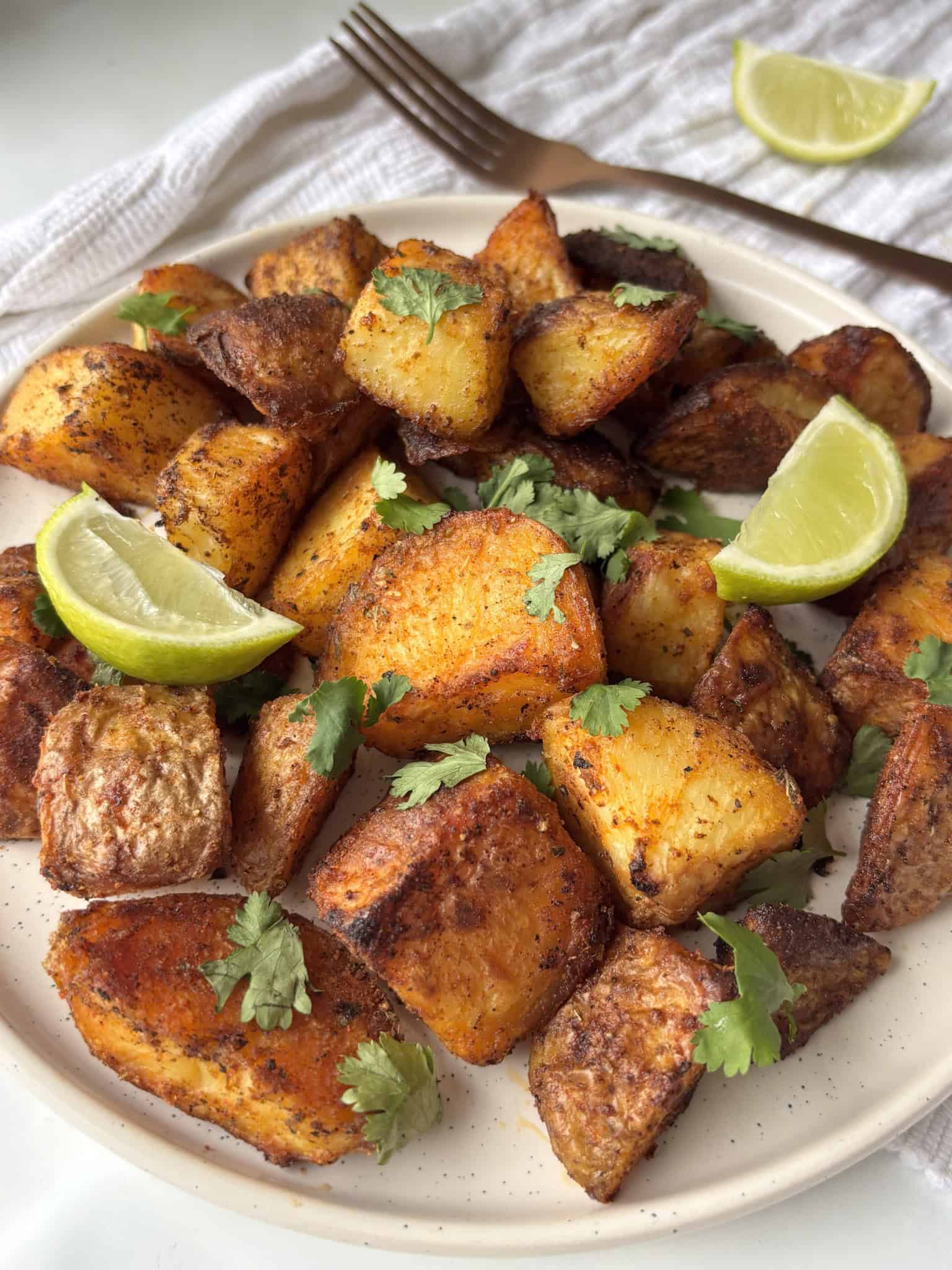 a close up photo of crispy Mexican potatoes topped with cilantro