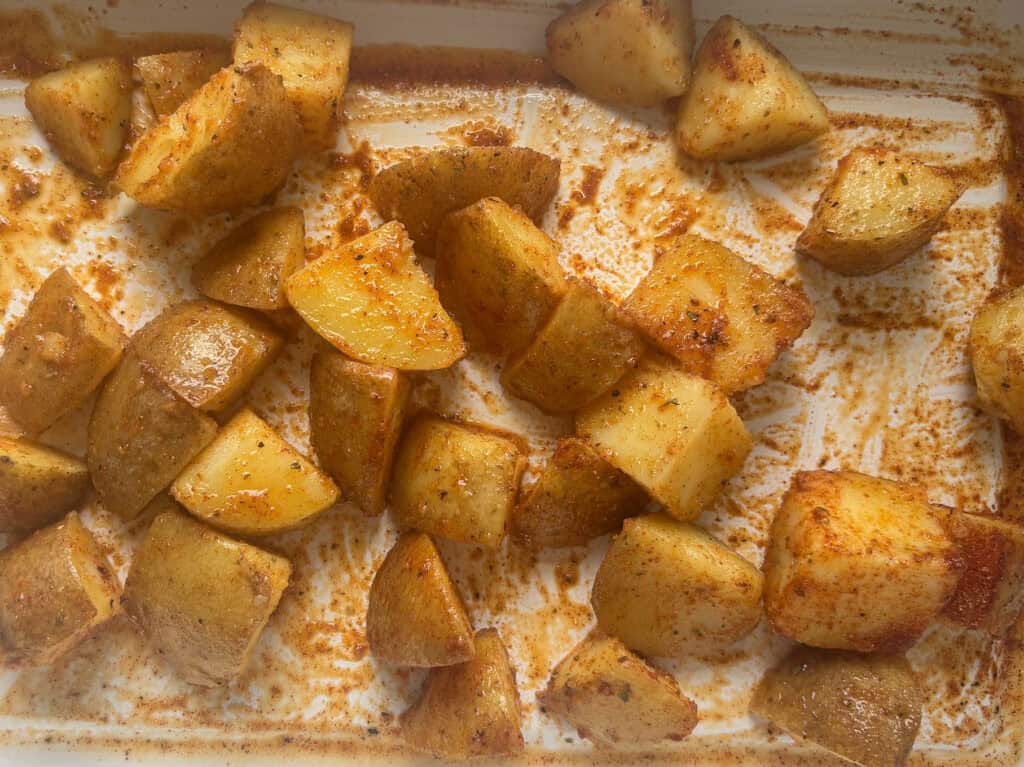 parboiled potatoes coated in the Mexican spices laid out flat on a baking tray before roasting