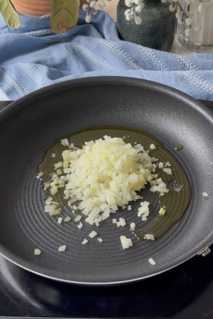 diced onion and garlic added to a pan with olive oil