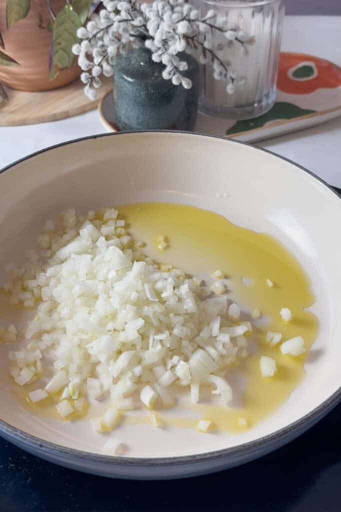 onion and garlic added to a pan with olive oil