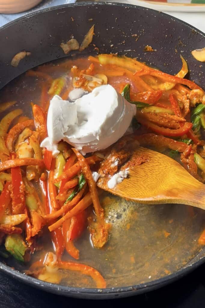 canned coconut milk is added to the saucepan along with the stir fry vegetables and red curry paste mixtures