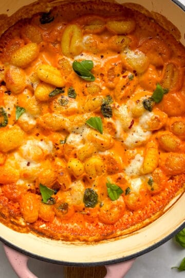 cheesy baked vodka gnocchi topped with fresh basil leaves