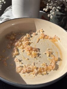 diced shallots and minced garlic being cooked in the oil for sun-dried tomatoes