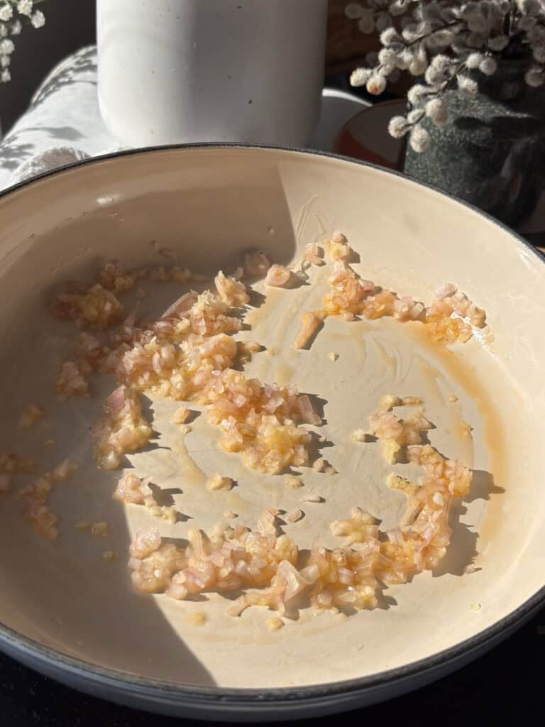 diced shallots and minced garlic being cooked in the oil for sun-dried tomatoes