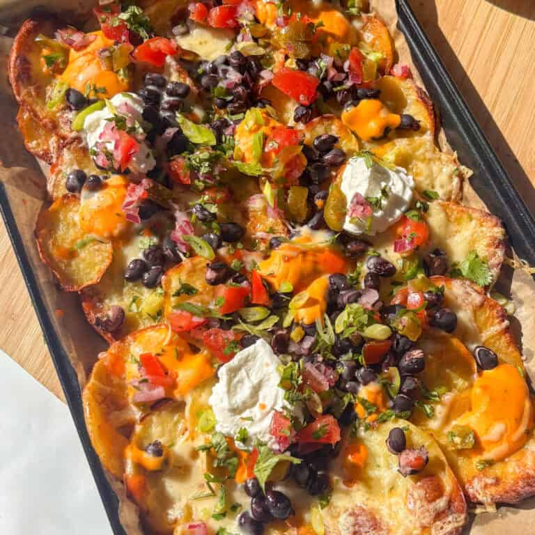 a tray of potato nachos topped with cheese, black beans, and tex-mex toppings