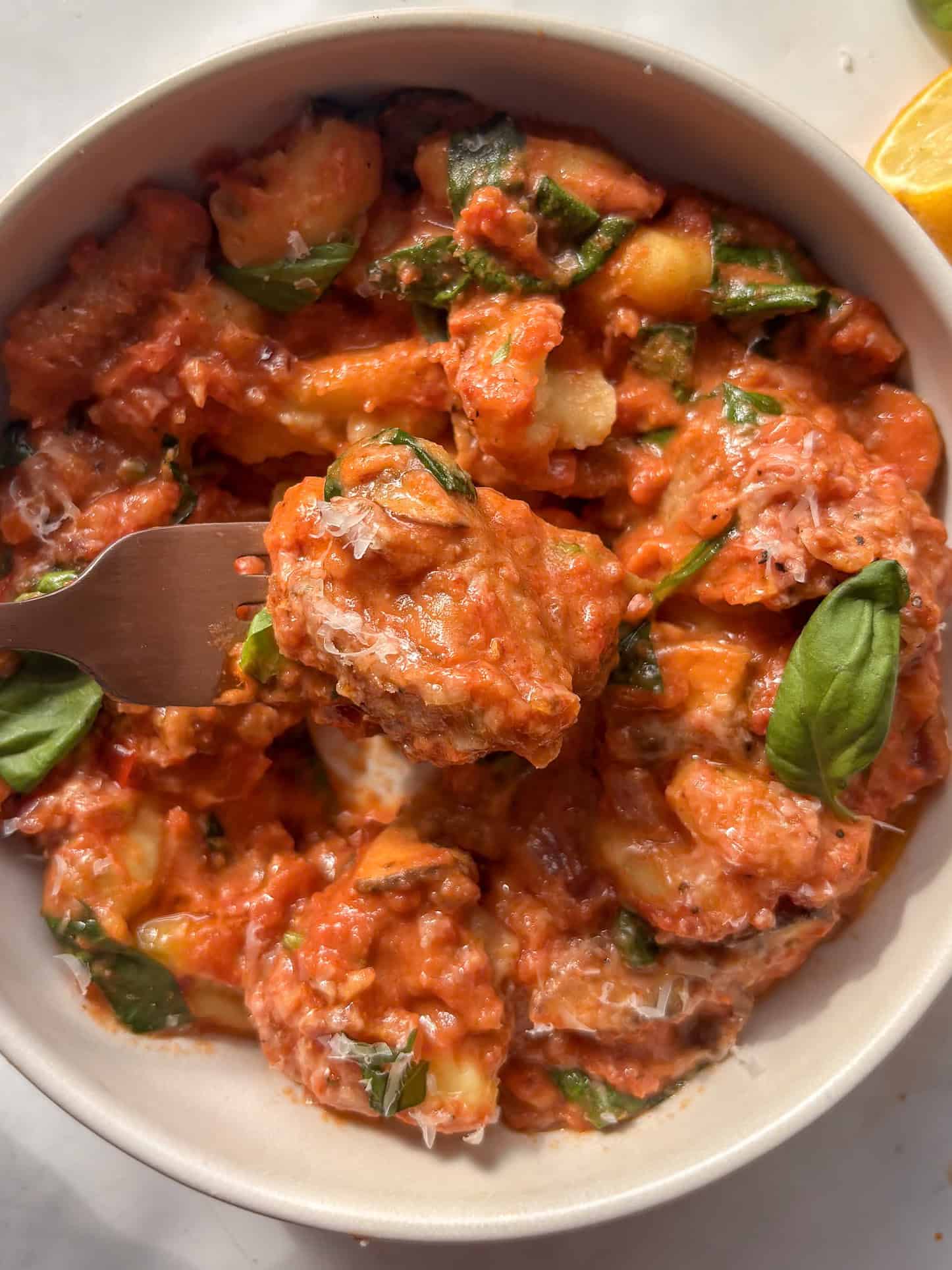 a forkful of creamy sausage gnocchi being held just above the bowl