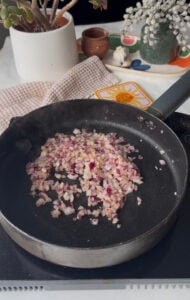 diced red onion and minced garlic being cooked in a pan in oil