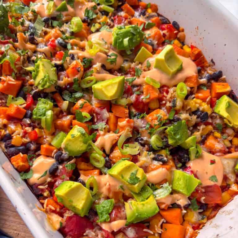 a casserole dish of black bean casserole topped with cubed avocado, cilantro, and spring onion