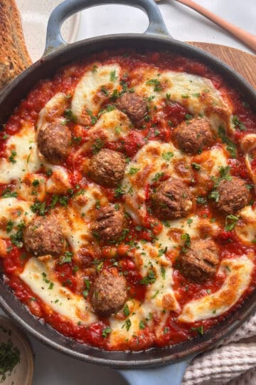 a skillet of cheesy meatballs in a white bean tomato sauce
