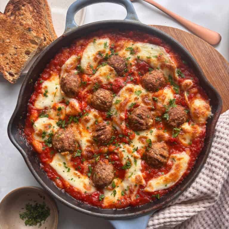 a skillet of cheesy meatballs in a white bean tomato sauce