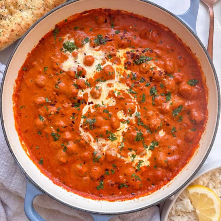 a casserole pan of creamy chickpea tikka masala topped with cream, cilantro, and red chili flakes