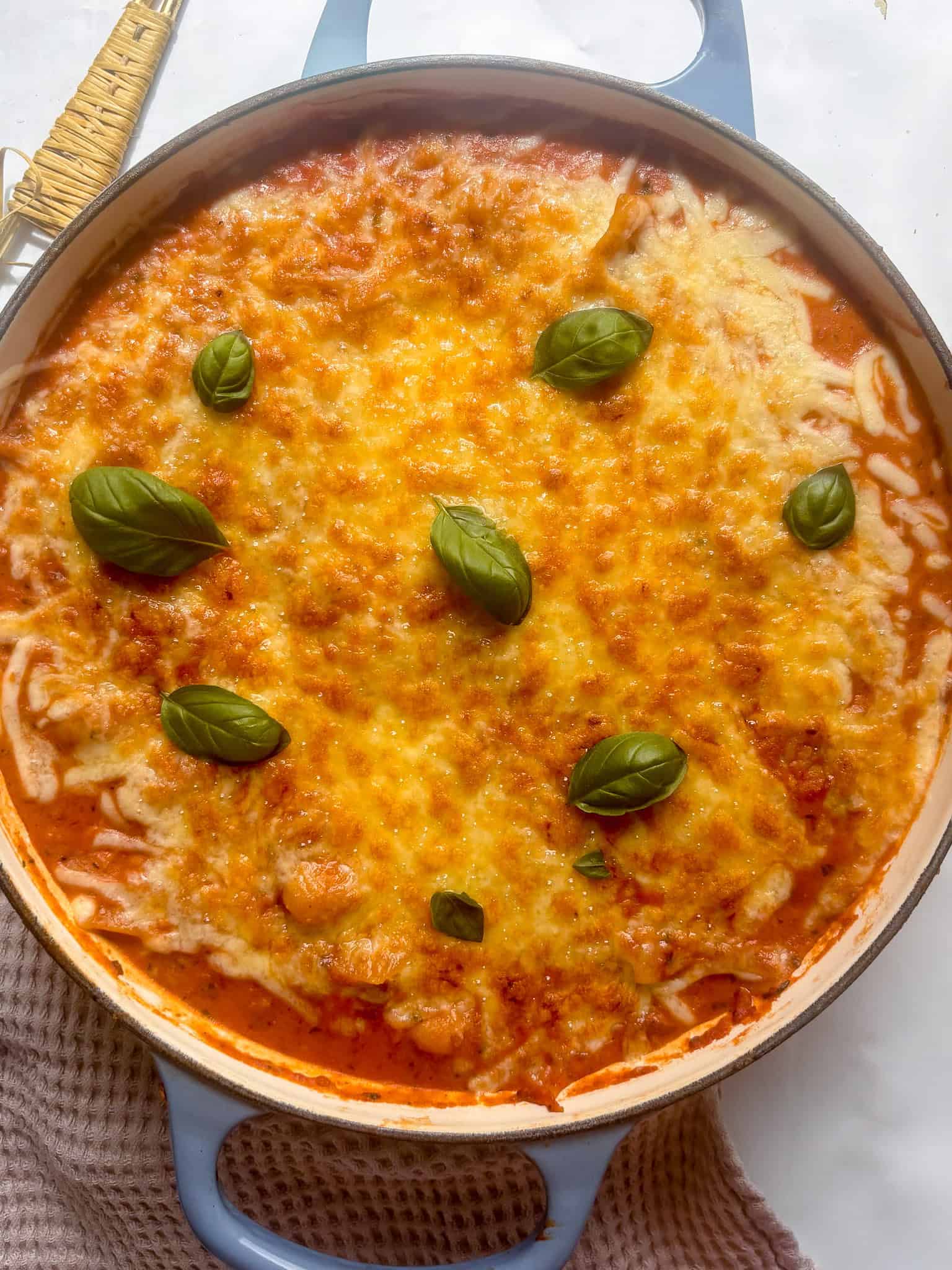 a casserole pan of butter bean and sun-dried tomato lasagne topped with fresh basil