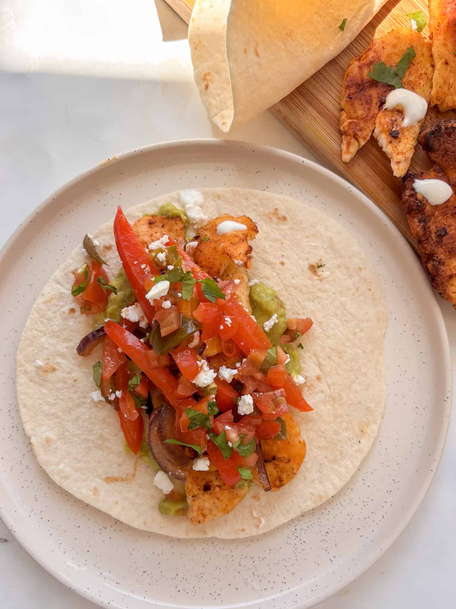 roasted peppers and halloumi stacked on top of tortilla with guacamole, pico de gallo, and crumbled feta