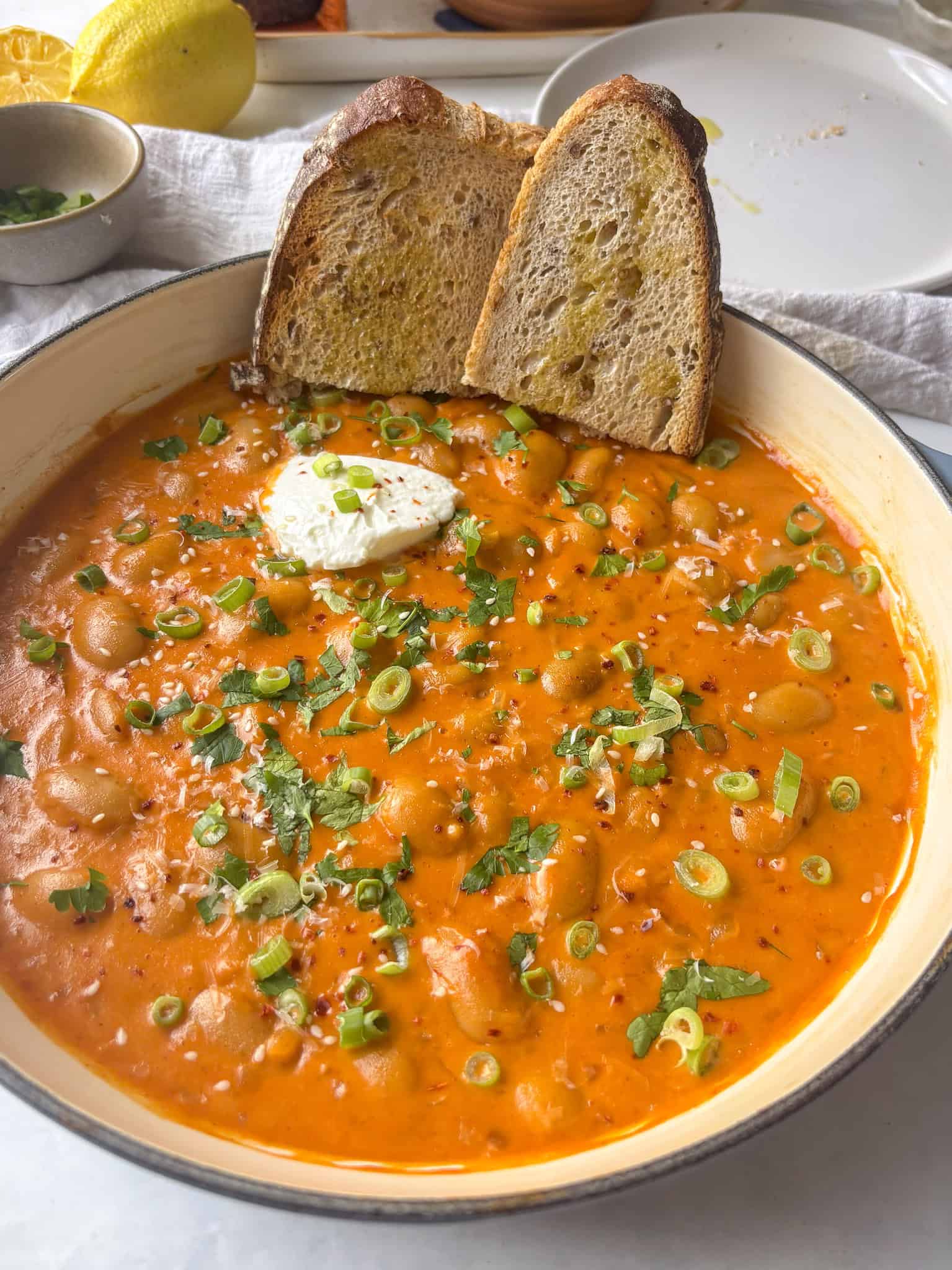 creamy gochujang beans topped with sliced spring onions, sesame seeds, cilantro, and served with two slices of toasted sourdough