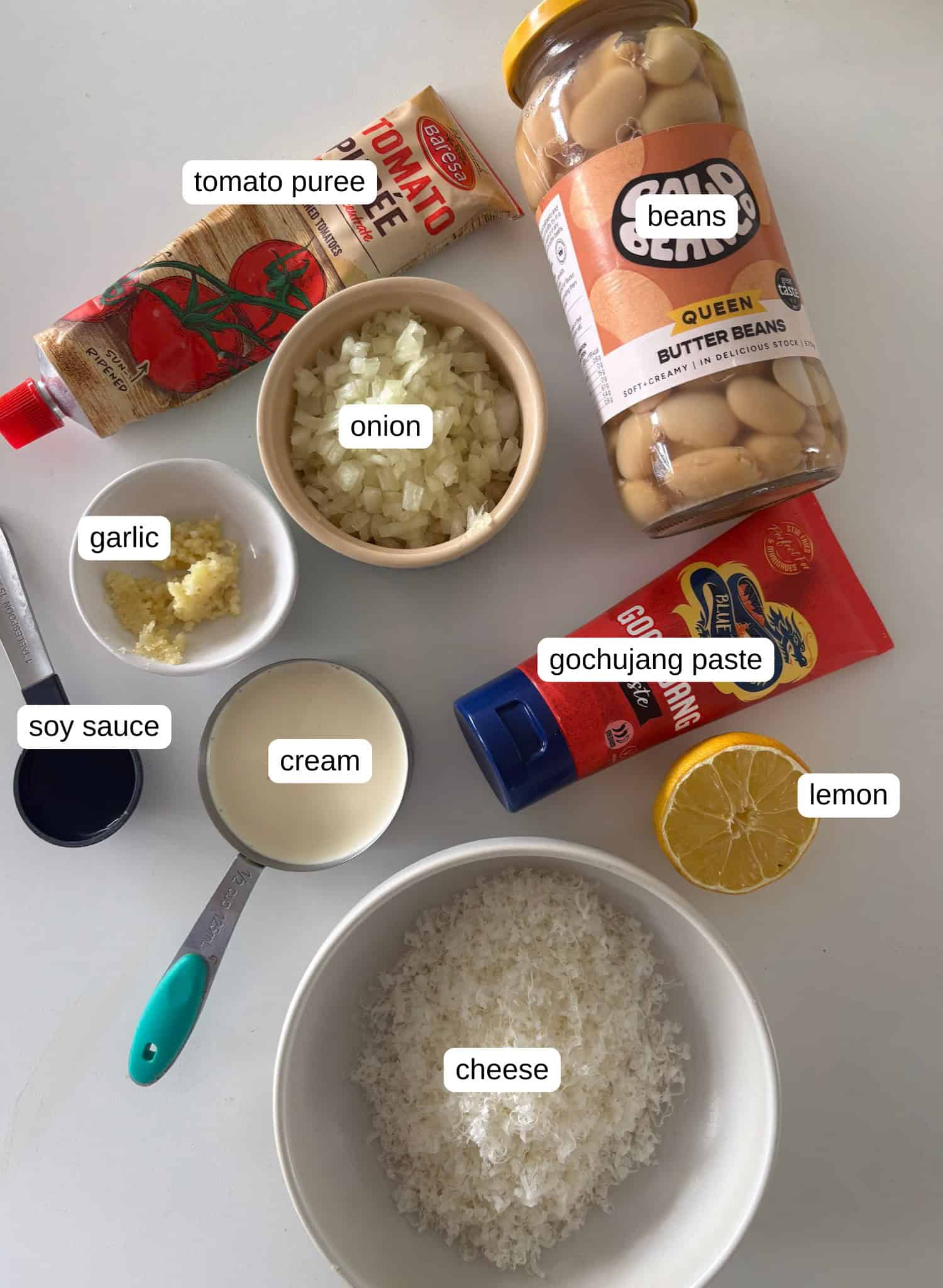 ingredient notes for the gochujang butter beans: you'll need oil and butter (not pictured), onion, garlic, soy sauce, gochujang paste, cream, cheese, butter beans, lemon, tomato puree