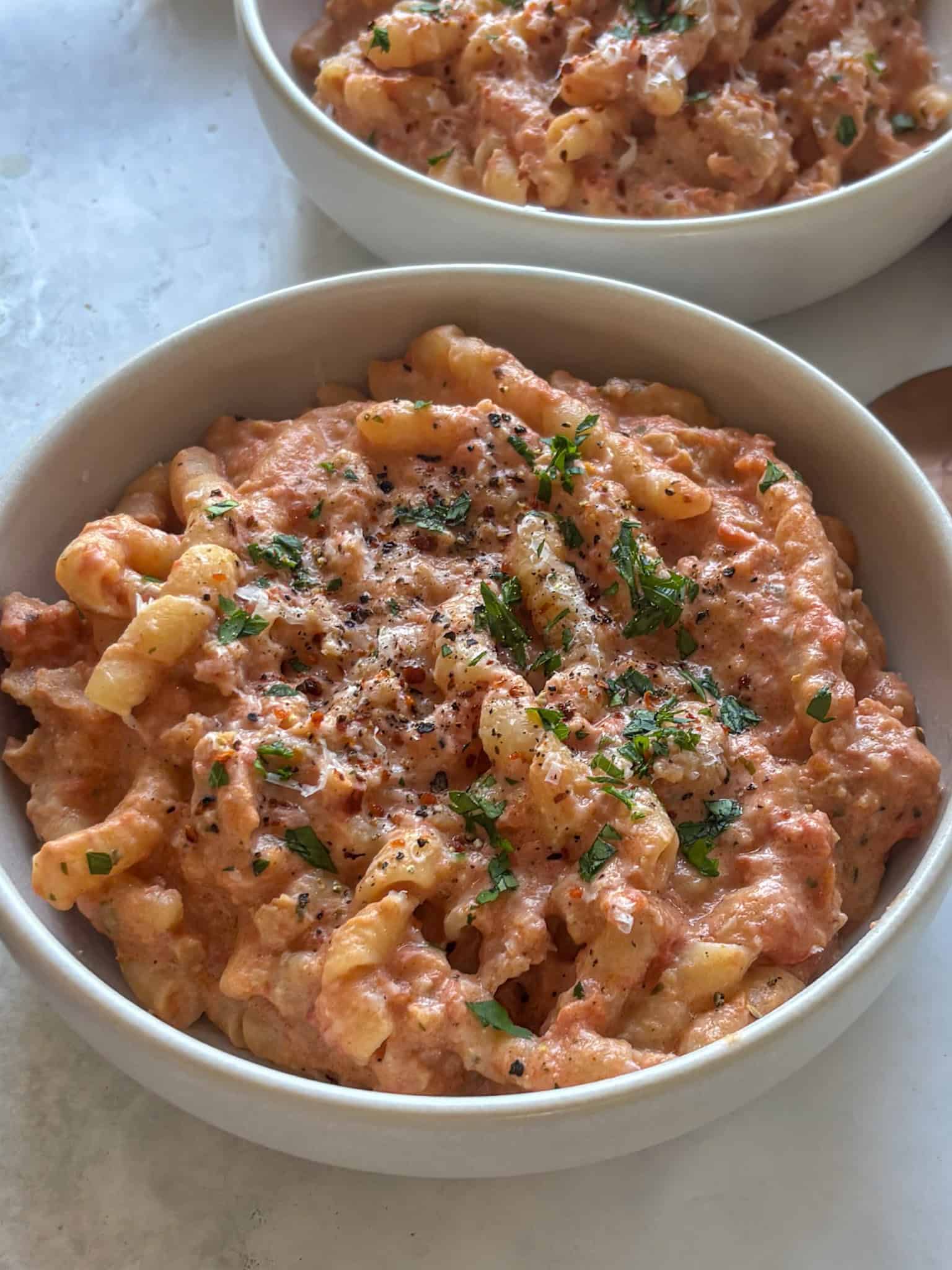 a bowl of Boursin cheese pasta, topped with fresh herbs and chili flakes.