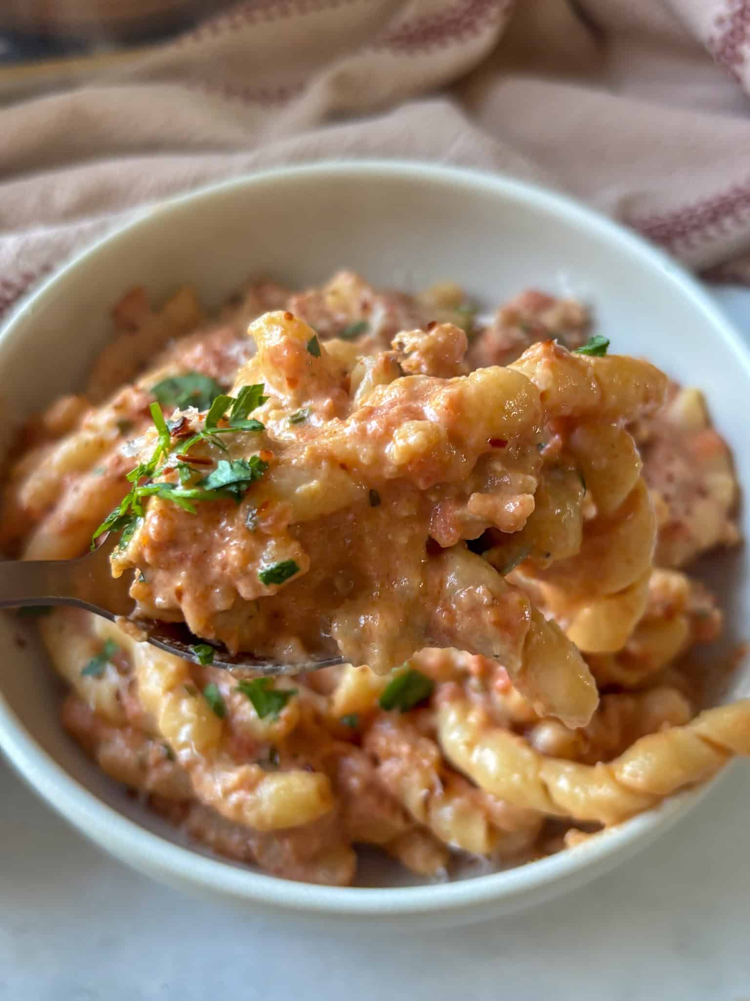 a close up shot of Boursin cheese pasta made with tomatoes, fresh herbs, and chili flakes to garnish