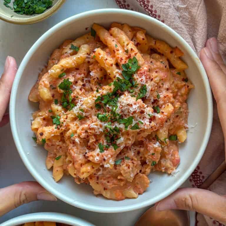 a bowl of boursin cheese pasta topped with parmesan and fresh herbs