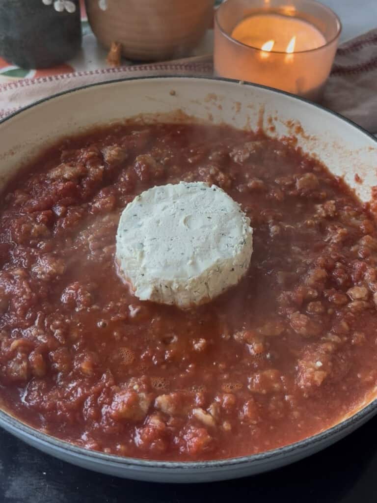the block of Boursin garlic and herb cheese added to the crumbled sausage and tomato sauce