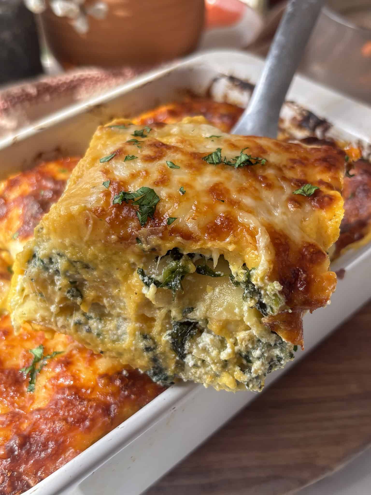 a portion of butternut squash and spinach lasagne being removed from the pan