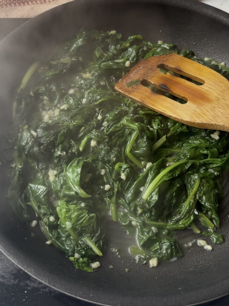 spinach being wilted in a pan with minced garlic