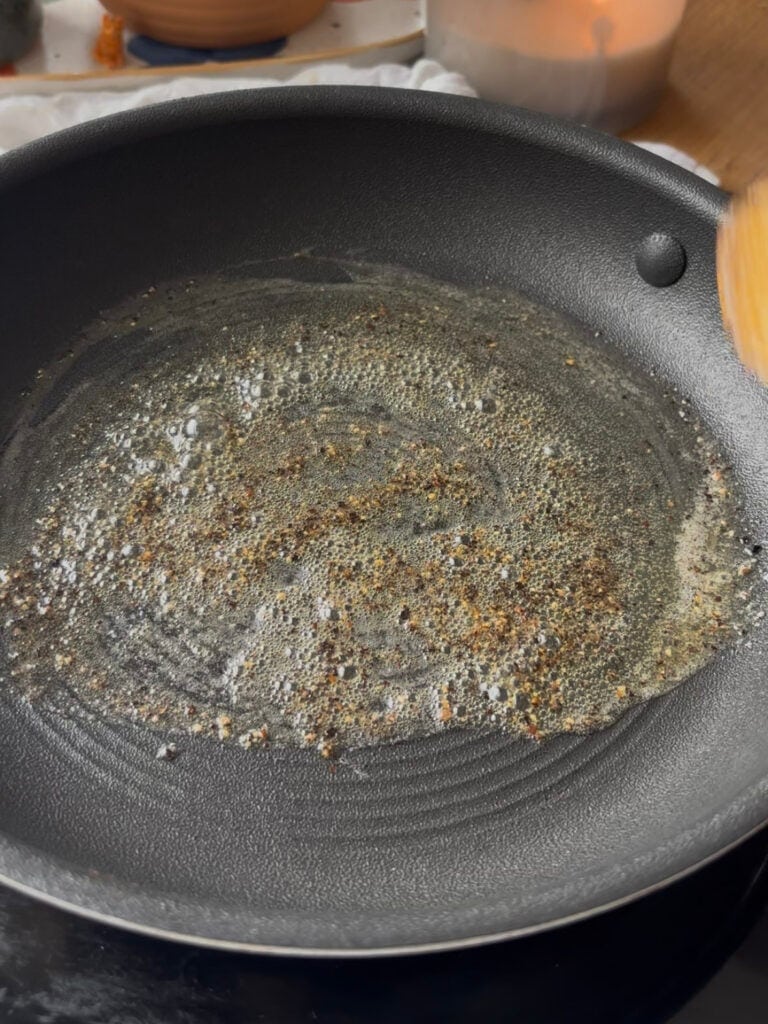black pepper is bloomed in a pan with melted butter before making the cacio e pepe