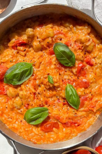 cherry tomato orzo topped with fresh basil in a skillet