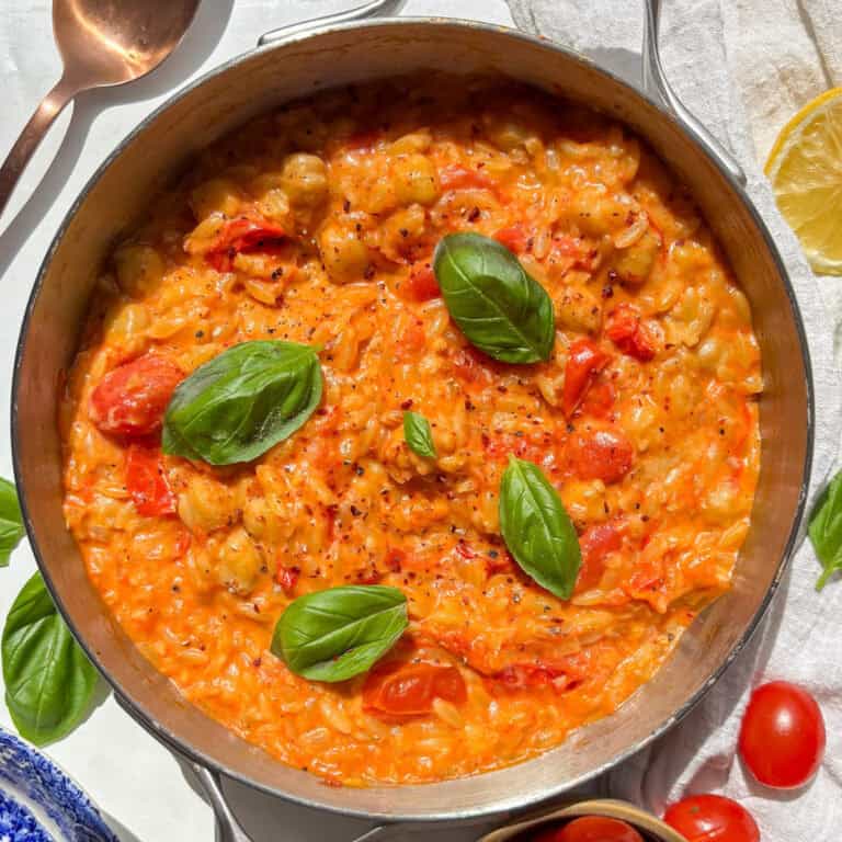 cherry tomato orzo topped with fresh basil in a skillet