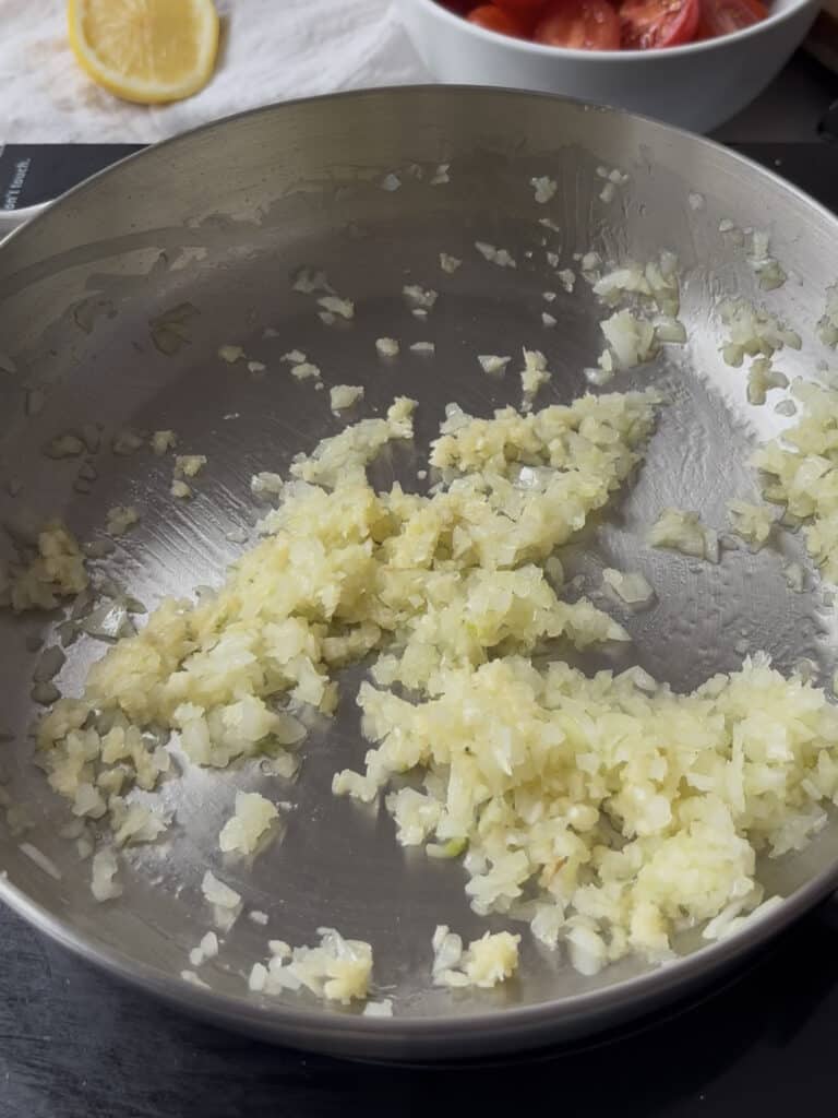 diced onion and garlic being cooked in olive oil in a pan