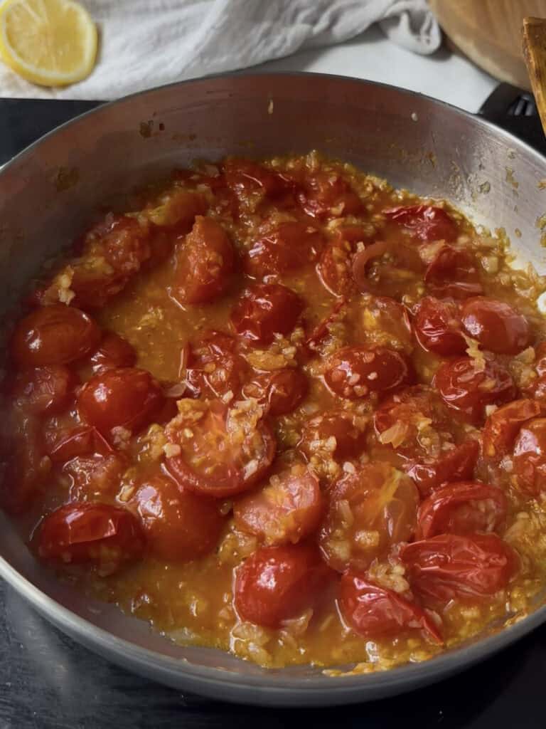 halved cherry tomatoes are cooked along with diced onion and garlic in olive oil until the tomatoes soften and relased their juices