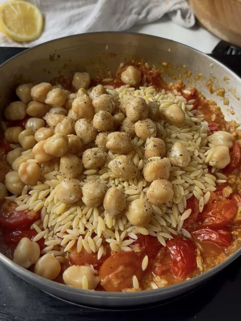 orzo and chickpeas are added to the blistered cherry tomatoes along with salt and pepper