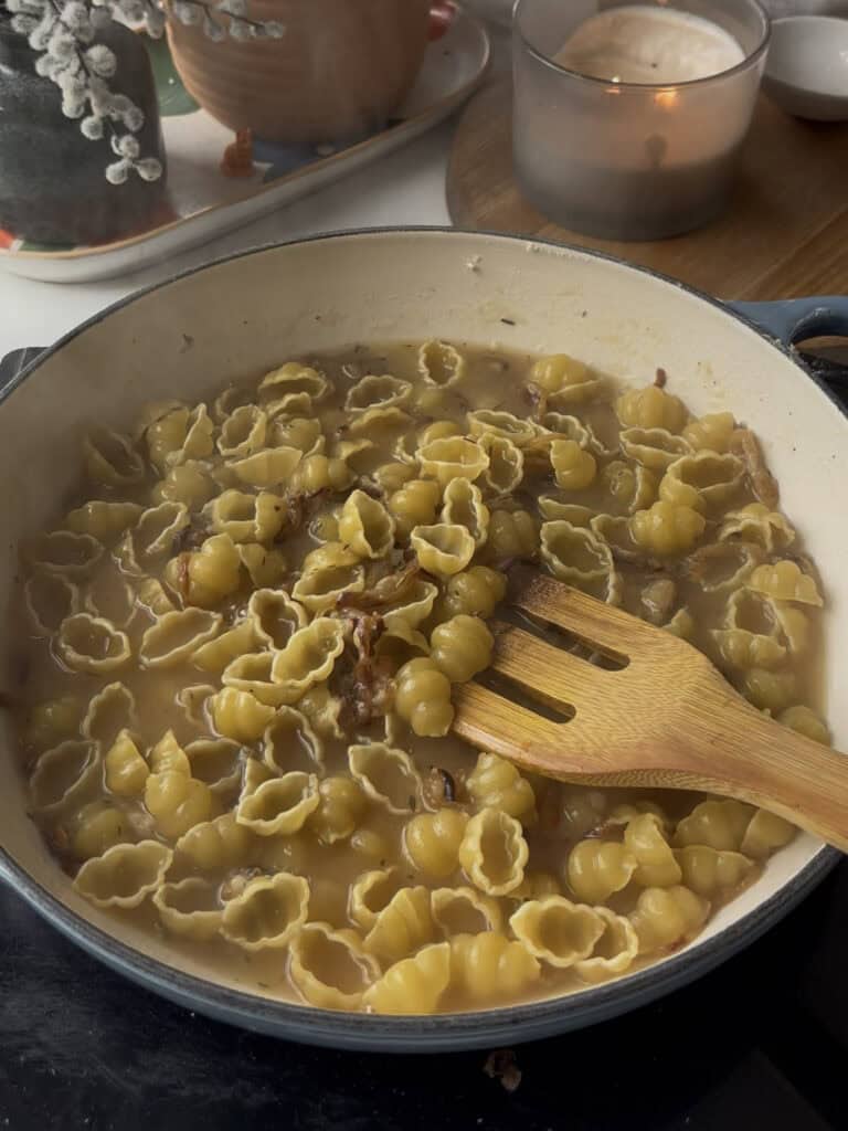 pasta cooks in the vegetable stock and caramelised onion sauce to make the base of the french onion pasta - ready for cream and cheese to be added