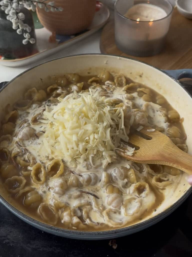 grated cheese is added to the french onion pasta to be swirled into the sauce